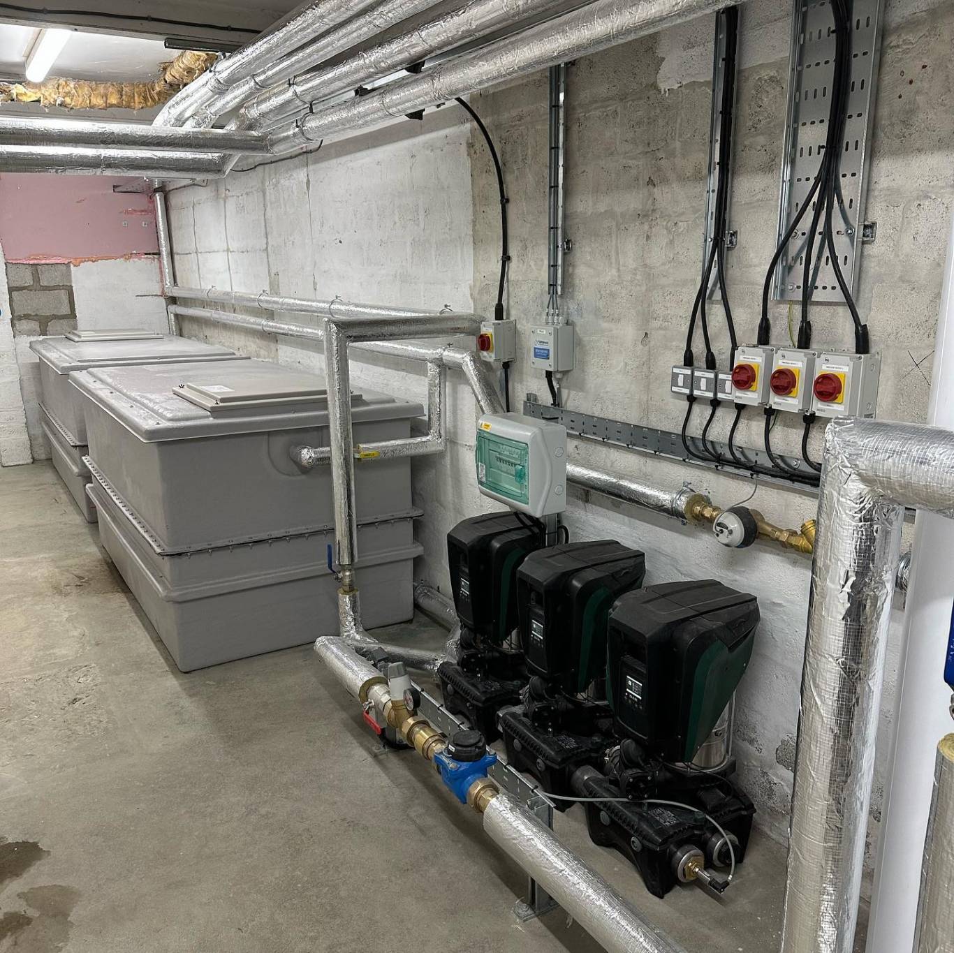 Plant room with GRP cold water storage tanks and a triple booster pump set